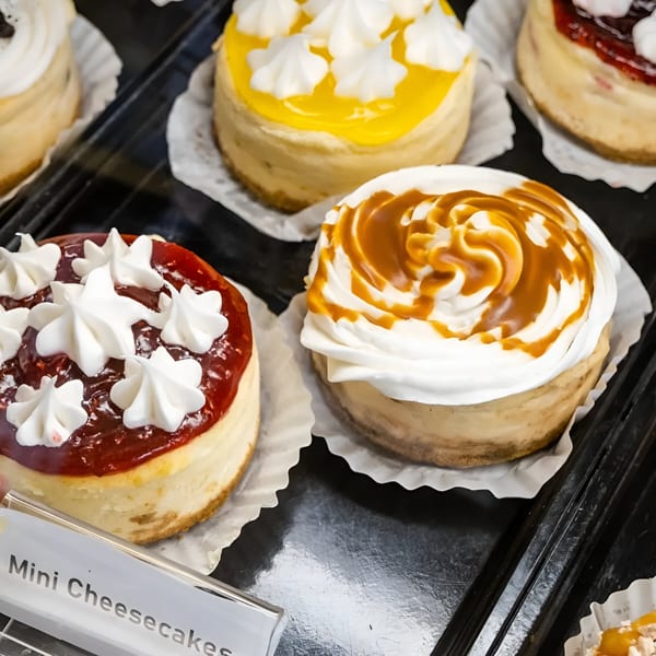 Assortment of mini cheesecakes with various toppings, including strawberry, caramel, and lemon.