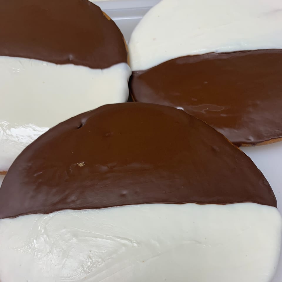 Close-up of several black and white cookies with half chocolate and half vanilla frosting.